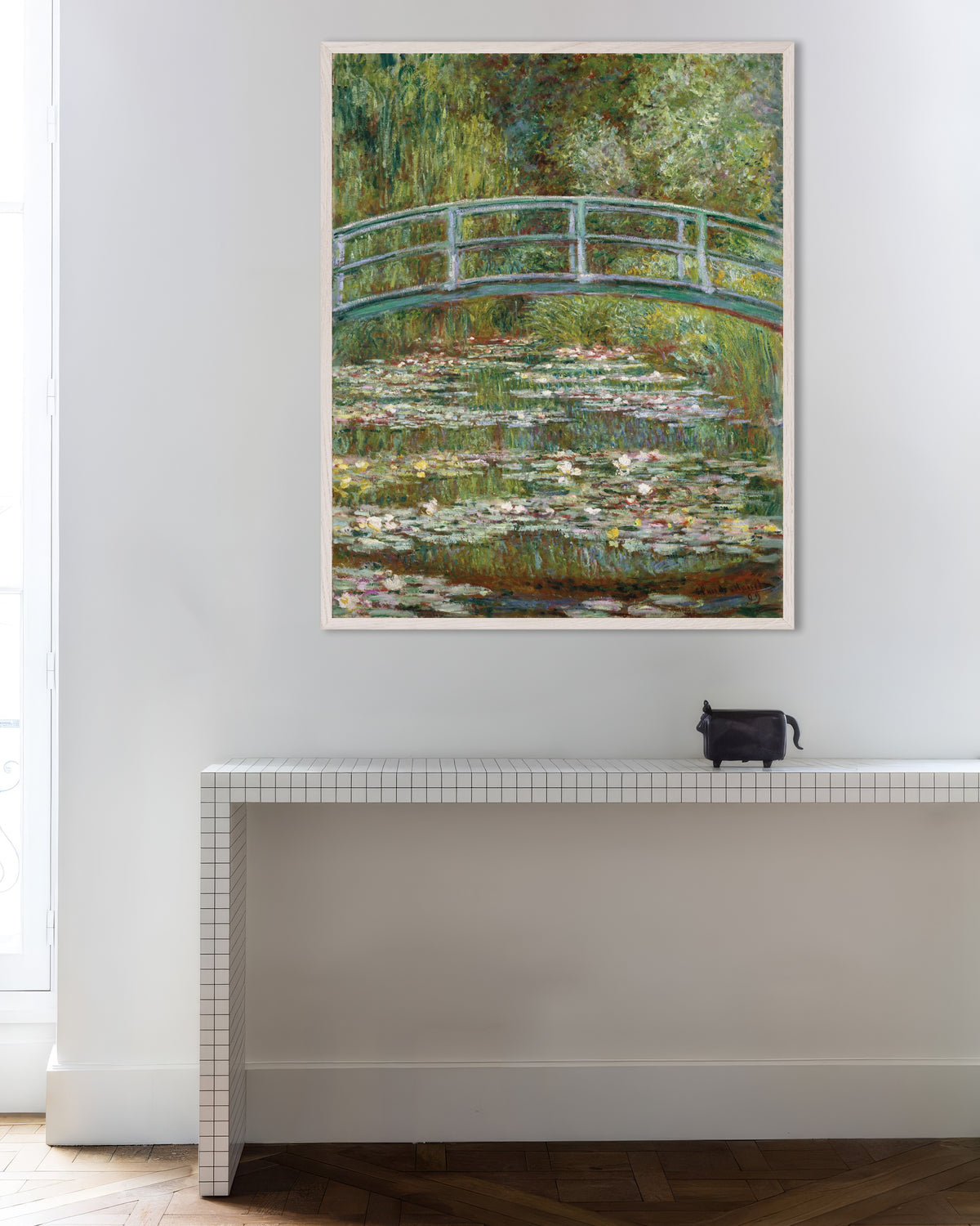 Claude Monet’n Silta lumpelammen yllä (1899) -juliste valkoisessa puukehyksessä