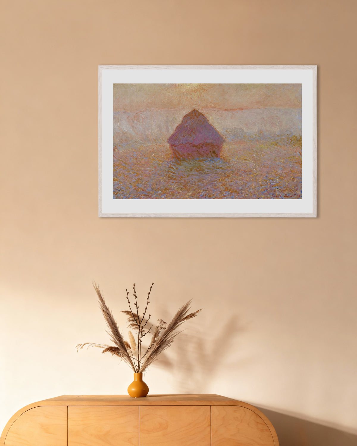 Claude Monet’n Viljasuova, aurinko usvassa (1891) -juliste valkoisessa puukehyksessä