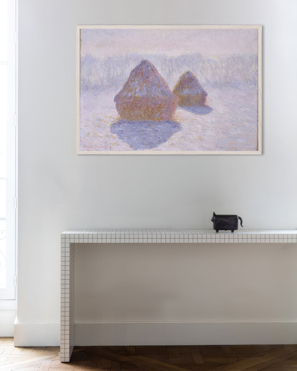 Claude Monet’n Viljasuovat, lumi ja aurinko (1891) -juliste valkoisessa puukehyksessä